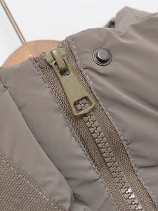 Detailed macro view of heavy-duty resin zipper and metal snap button on winter hooded jacket