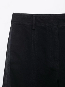 Gros plan d'un pantalon en jean noir avec bandes décoratives grises et passants de ceinture