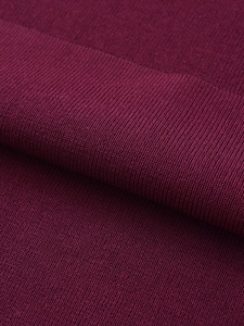 Vue macro de la texture en maille côtelée bordeaux avec coutures fines sur une robe