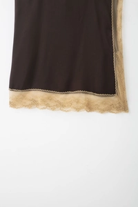 Détail de tissu en soie marron foncé avec bordure en dentelle dorée pâle sur l'ourlet