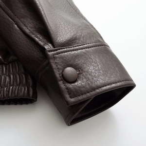 Detailed view of dark brown PU leather jacket featuring elastic hem and snap button cuffs