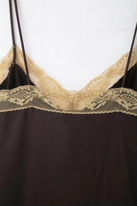 Détail macro du haut marron foncé avec dentelle florale dorée complexe au décolleté