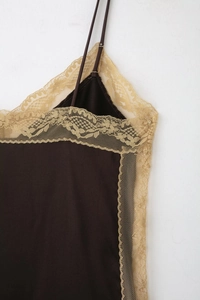 Détail de la bordure en dentelle délicate et fines bretelles sur un caraco marron foncé
