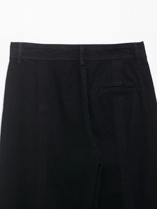 Détail de la taille et de la poche arrière sur un pantalon noir droit avec des franges