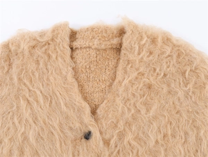 Détail du cardigan duveteux beige avec col en V et texture de maille effet fourrure