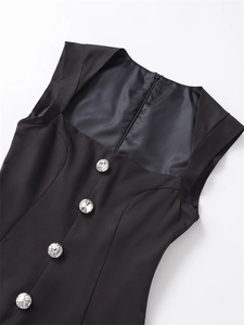 Detail des eckigen Ausschnitts mit funkelnden Kristallknöpfen auf schwarzem Jumpsuit