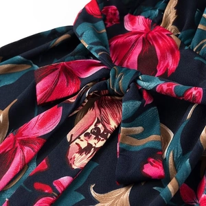 Dettaglio dell'abito con stampa floreale, scollo a V ed elegante fiocco in vita