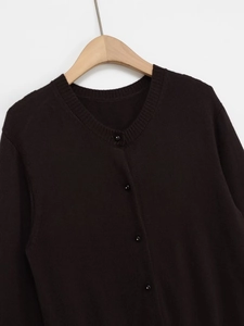 Dettaglio del collo a costine e bottoni su cardigan in maglia di colore scuro