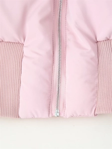 Détail de la fermeture éclair argentée et de l'ourlet côtelé sur veste rose