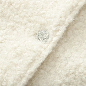 Détail du tissu en laine blanche et bouton bijou orné de strass sur la veste pour femme