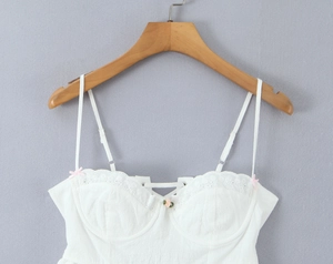 Close-up of white lace bustier top featuring pink bow and rose flower detail
