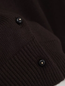 Macro della maglia marrone scuro con bottoni neri di design e dettagli in metallo dorato