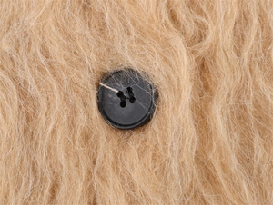Vue macro du tricot pelucheux marron clair avec bouton noir mat à quatre trous