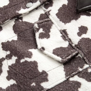 Macro detail of cow print faux fur texture with embossed silver button and leather collar