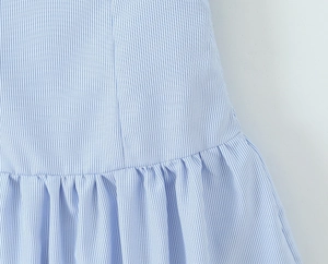 Macro detail of light blue and white striped fabric with pleated waist design