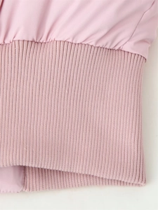 Gros plan de la veste d'hiver rose montrant le tissu lisse et le bord-côte élastique