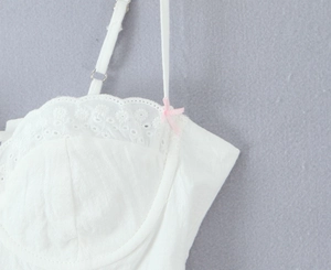 Detail of white top showing delicate eyelet lace embroidery and a small pink bow detail