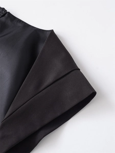 Detailaufnahme des schwarzen Jumpsuits mit feinen Falten und dezentem verdecktem Reißverschluss