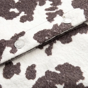 Macro shot of faux shearling cow print jacket with embossed metallic silver buttons