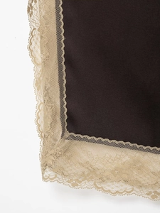 Détail macro de dentelle champagne brodée sur le tissu foncé d'un ensemble deux pièces