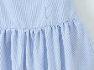Detailed view of light blue striped seersucker fabric with elegant gathered waist pleats