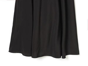 Gros plan de l'ourlet de robe noire montrant le tissu soyeux et les coutures fines