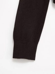 Dettaglio della manica del cardigan nero con polsino a coste e trama in maglia