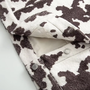 Close-up of cow print jacket featuring silver metal buttons and premium fuzzy texture