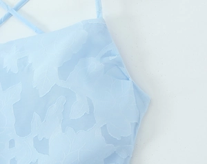 Close-up of light blue floral jacquard fabric and thin criss-cross back straps