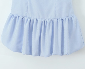 Detail of light blue striped dress showing ruffled hemline and smocked fabric textures