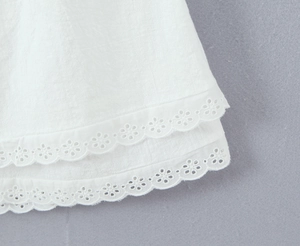 Detail of white cotton hem with delicate double-layered lace and floral embroidery