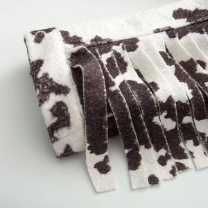 Detail of soft cow print fabric with fringe edges and brushed wool texture finish