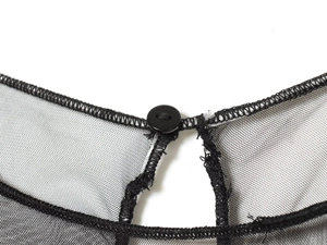 Détail du tissu en maille noire avec fermeture à bouton brillant et coutures nettes