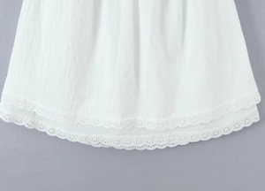 Detailed close-up of double-layered white cotton hem with delicate eyelash lace embroidery