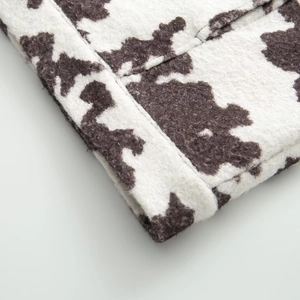 Detailed macro view of the cow print fabric texture and fine stitching on the jacket sleeve