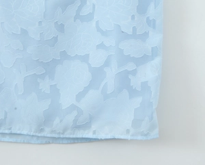 Close-up of light blue burnout chiffon fabric with intricate 3D rose floral pattern
