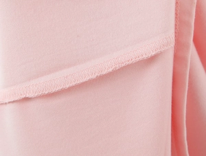 Macro shot showing high-quality overlock stitching and knit fabric of the pink dress