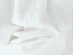 Close-up of white textile fabric texture with delicate lace trim and soft pleats