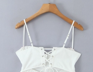 Detail of white cotton crop top featuring adjustable straps and lace-up back design