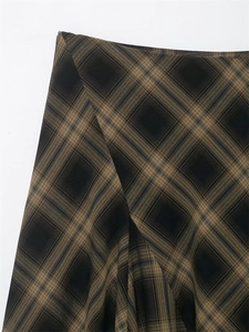Detailed close-up of vintage plaid skirt fabric with premium brown and beige checkered weave