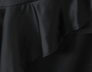 Macro shot of tiered black ruffle hem detail with fine stitching on a sleek polyester dress