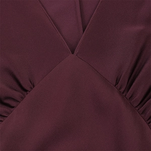 Detail of elegant wine red deep V-neckline with pleated texture on satin dress