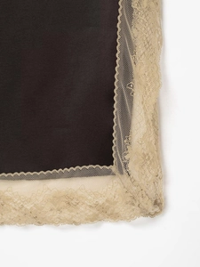 Détail du tissu noir avec bordure en dentelle fleurie champagne sur l'ourlet de robe
