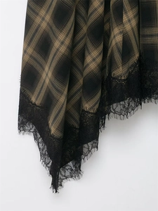 Detail of plaid skirt hem featuring elegant black floral lace trim and vintage check fabric