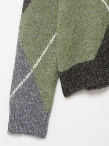 Dettaglio del maglione in maglia a rombi con trama di lana soffice e polsini a costine