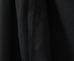 Detailed macro view of professional overlock stitching on black dress fabric texture