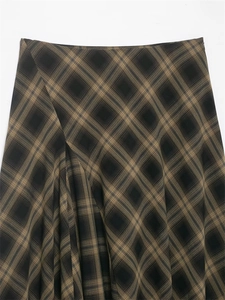 Close-up of winter high-waist plaid skirt with dark brown twill weave and pleats
