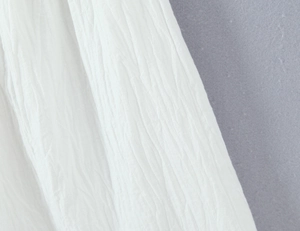 Detail shot of white crinkled fabric texture with a natural linen-like aesthetic and drape