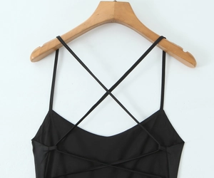 Detail view of the sleek crisscross back straps on a black satin slip dress