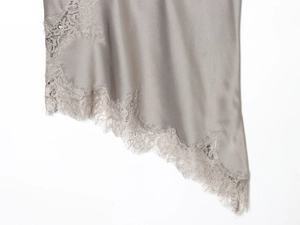 Close-up of grey satin fabric with delicate eyelash lace trim on the hemline detail